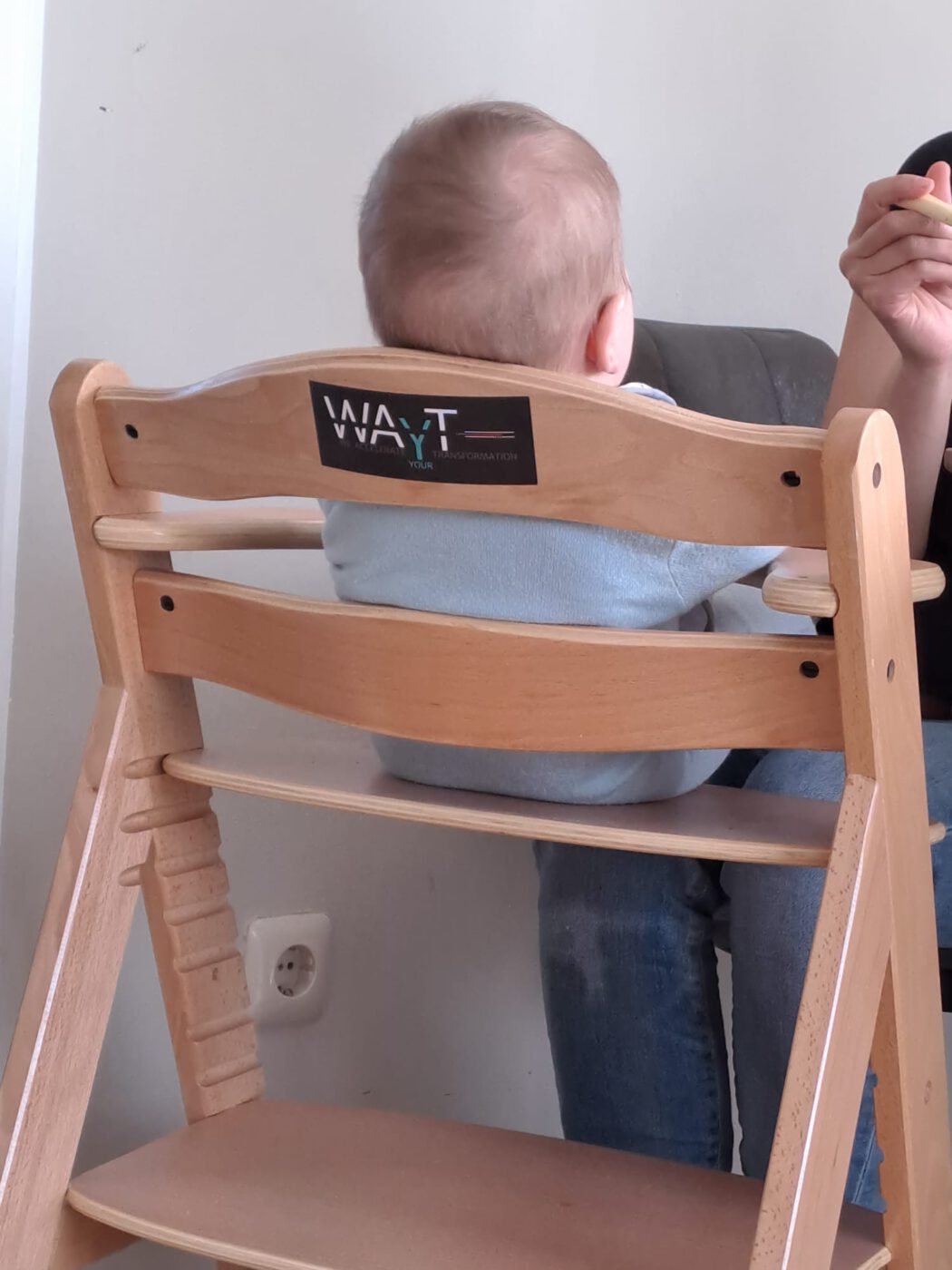 Ein Baby auf einem Babystuhl mit einem WAYT-Aufkleber
